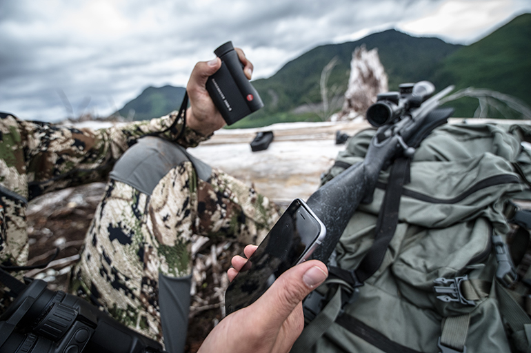rifle hunter holding phone and Leica rangefinder