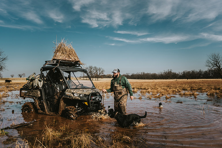 Duck hunter and dog in water with ATV