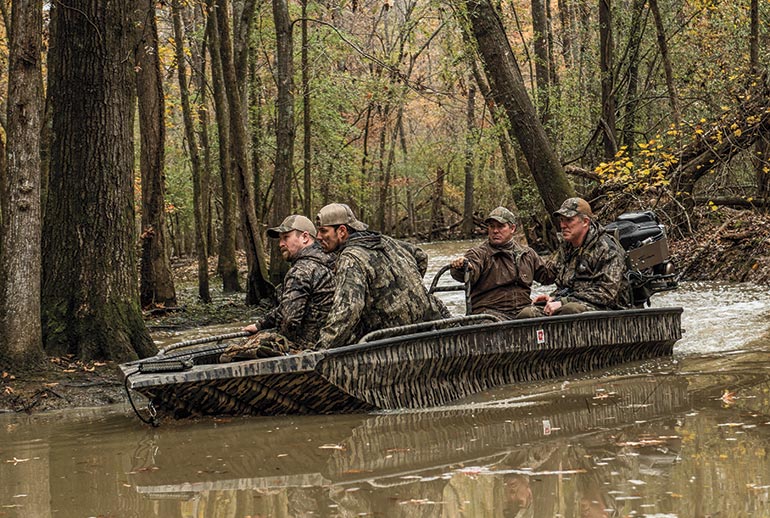Duck hunters in boat in timber