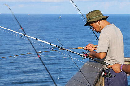 fisherman dropping sabiki rig off pier