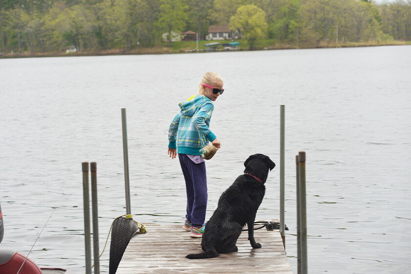 young girl with Lab puppy on dock