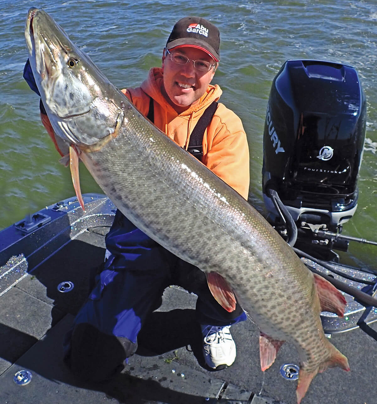 Angler Steve Ryan posing with a large muskie in a boat in open water