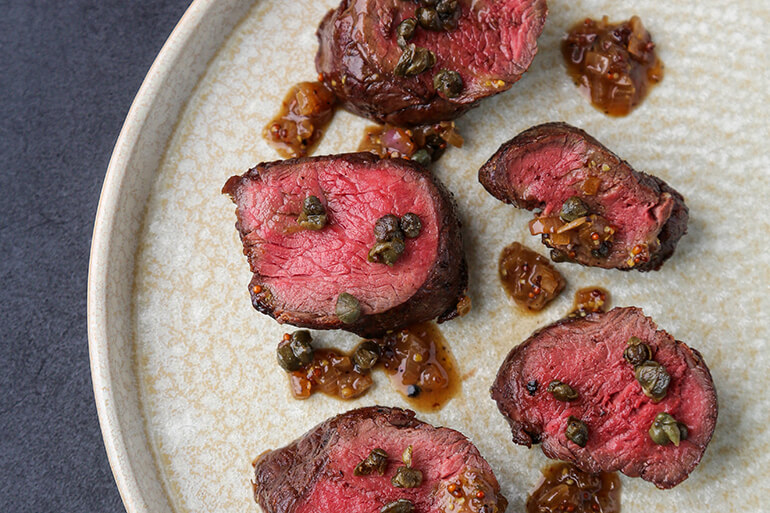 Venison backstrap medallions drizzled with a caper-mustard sauce