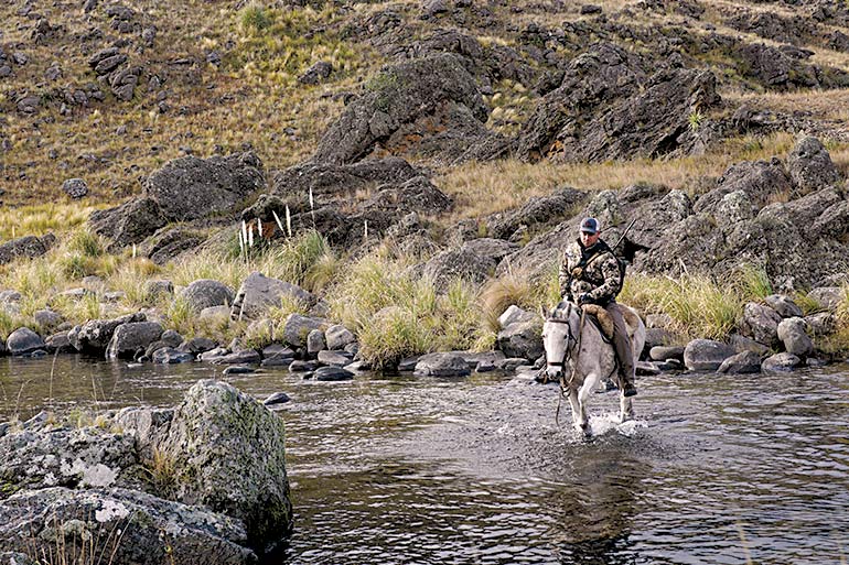 hunter riding horse across water in Argentina