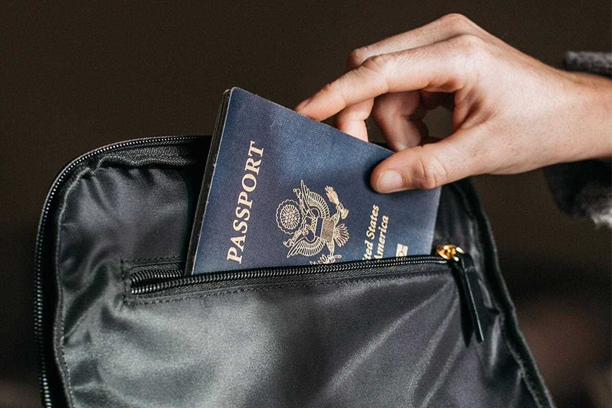 hand putting passport into pocket of bag