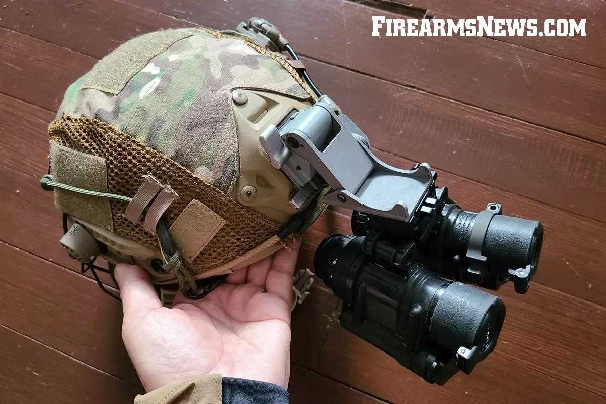 Hand holding a helmet with dual PVS-14 night vision goggles mounted