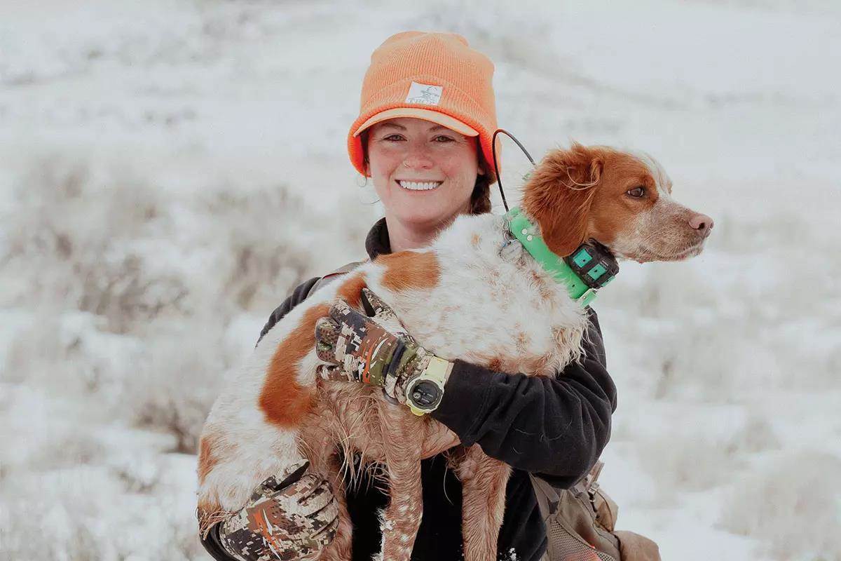 A woman upland hunter holding her hunting dog in her arms.
