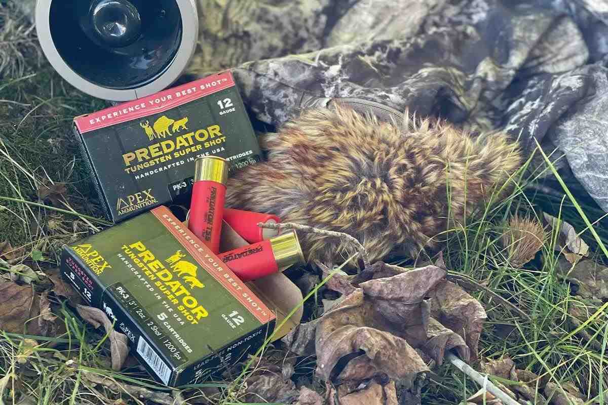 As box of predator hunting ammo and shotshells lie on the ground next to an e-caller.