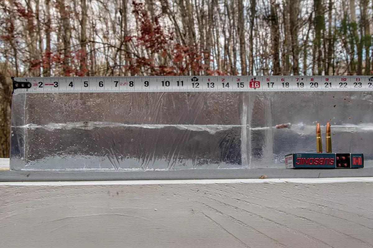 A block of ballistic gel block with a captured rifle round with a tape measure lying on top.  