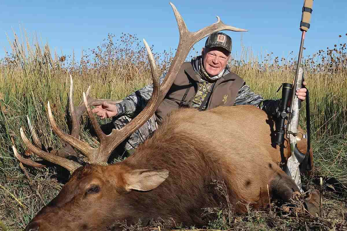 hunter with bull elk and rifle