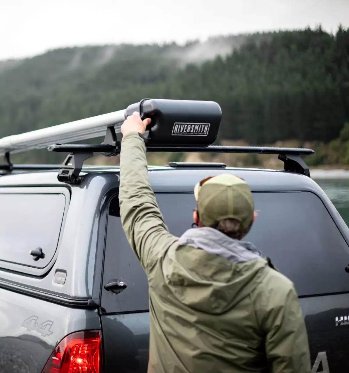 A fly angler opening a Riversmith roof-top fly-rod carrier. 