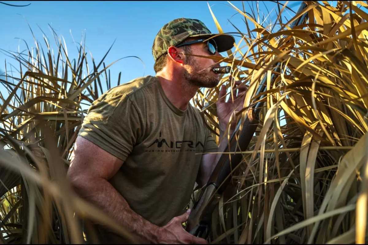 A hunter in a blind smoking a cigar.