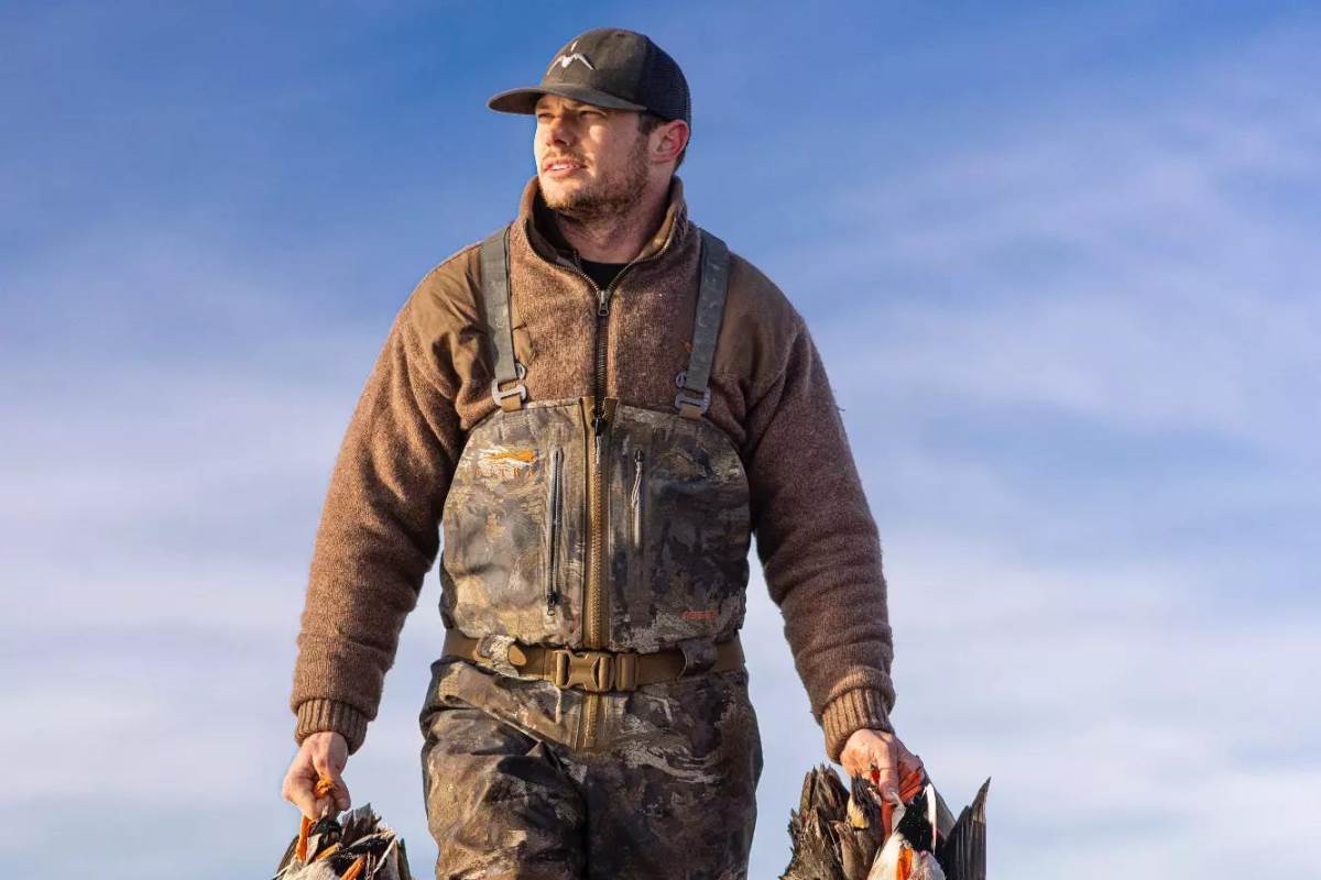 A hunter carrying dead ducks.