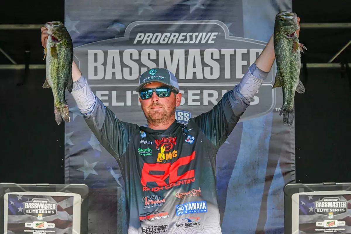 photo of man showing off fish on stage during tournament