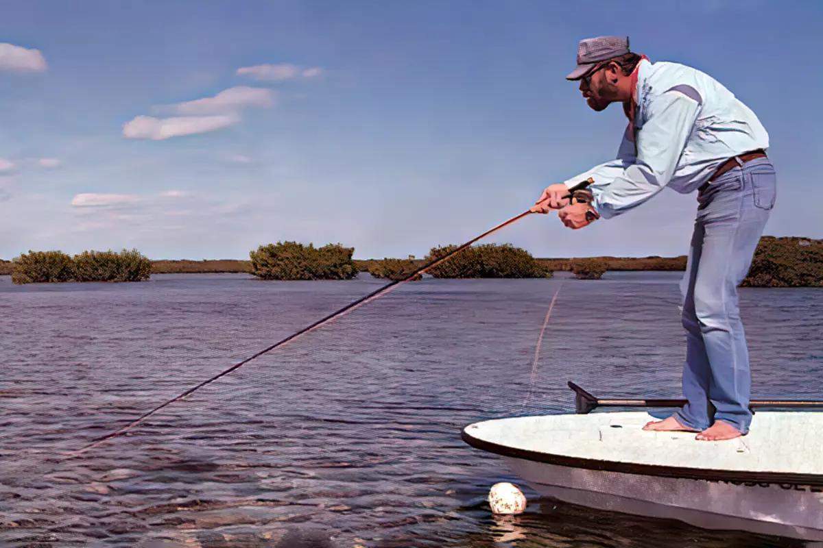 A fly angler standing on the deck of a flats boat intently watching his fly in the water.