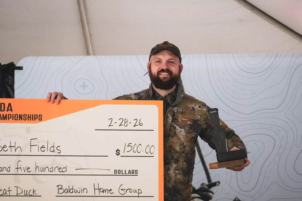 A duck caller with a trophy and a check.