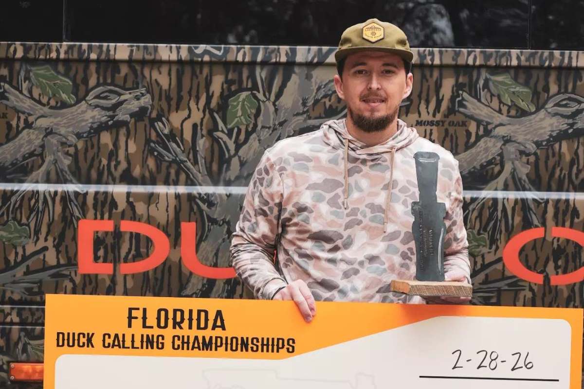 A duck caller with a trophy and check.