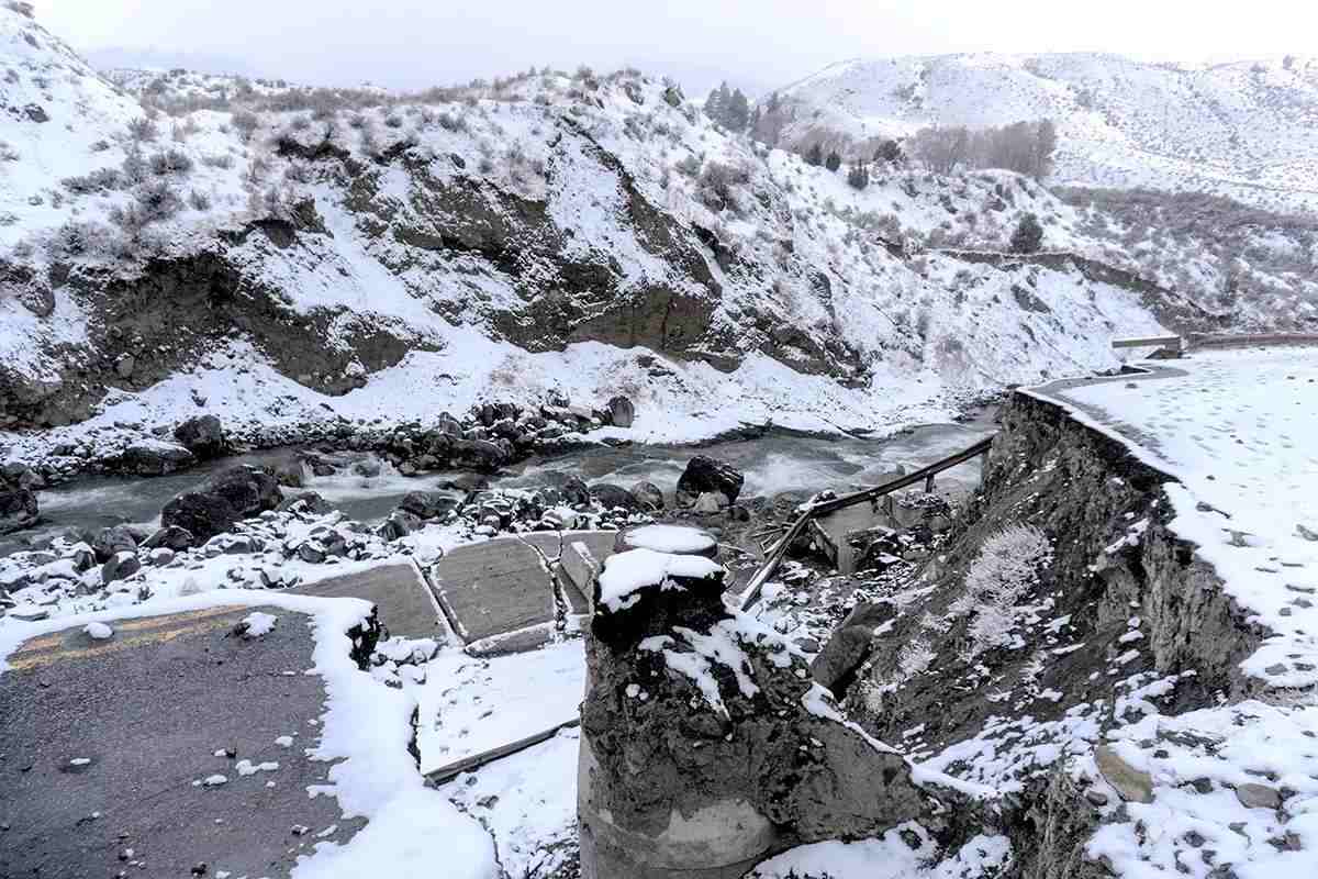 A snowy scene with a river at the bottom of a canyon; broken up roads in the foreground.