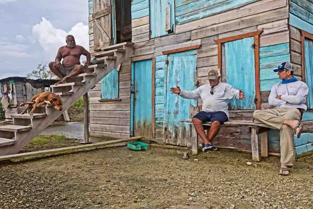 Belizean fishing guide Lincoln Westby holds his arms out telling a fish story at a rustic lodge. 