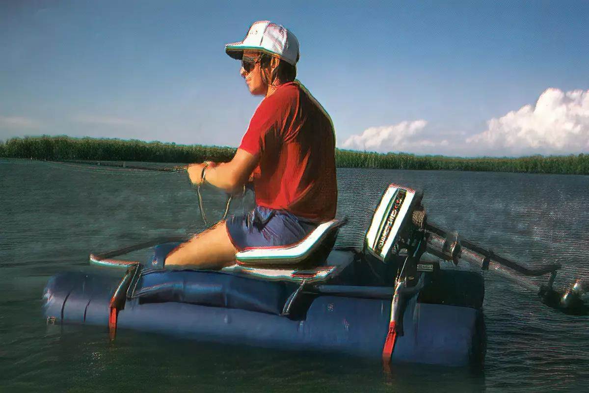 A fly angler sitting in a float tube on the water, an outboard motor attached at the rear.