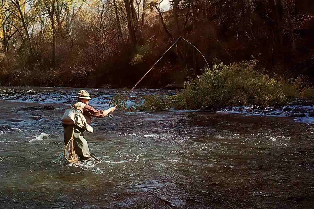 A fly angler wading knee deep, high-stick nymphing a swift section of river.