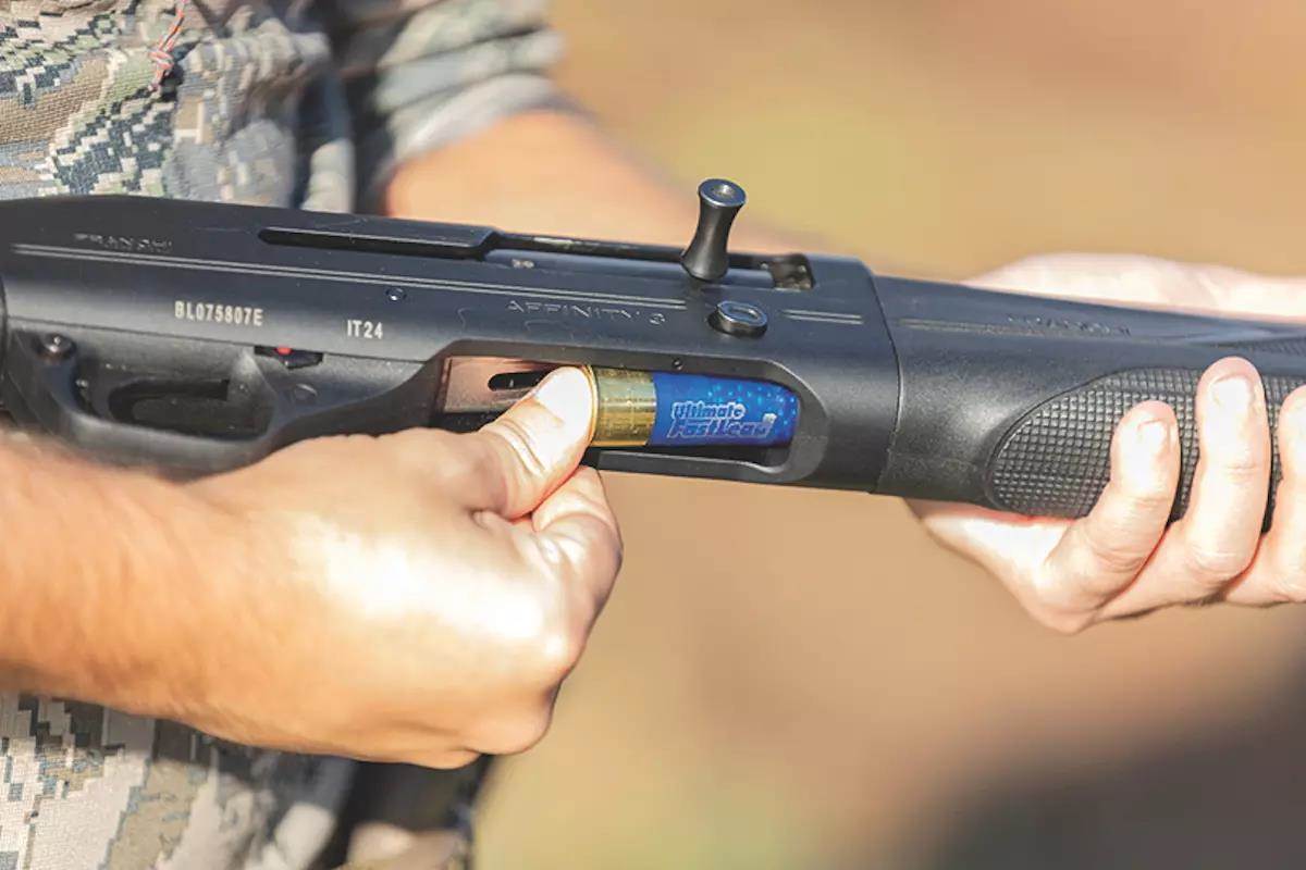 A shooter loads a shotgun shell into a semi-auto shotgun. 