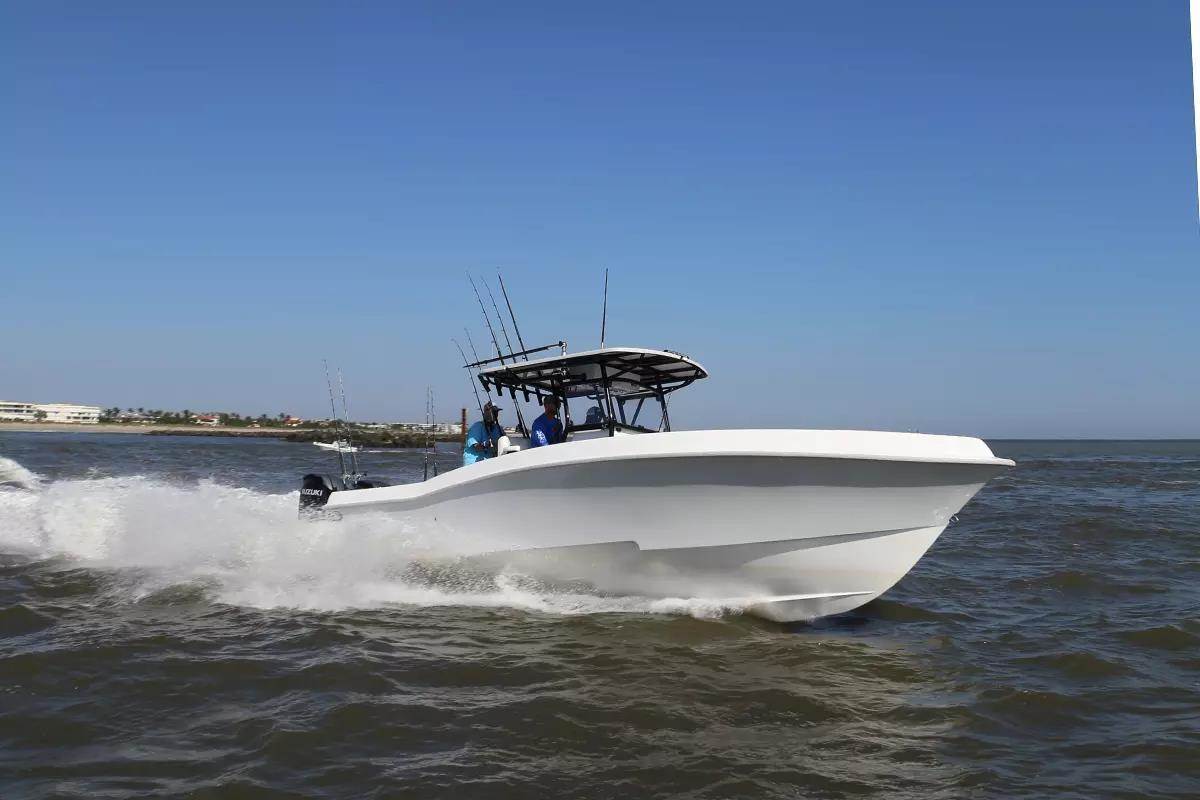 White outboard powered fishing boat runs into the ocean through an inlet