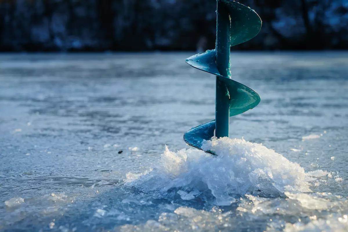 An ice auger sticks out of ice. 