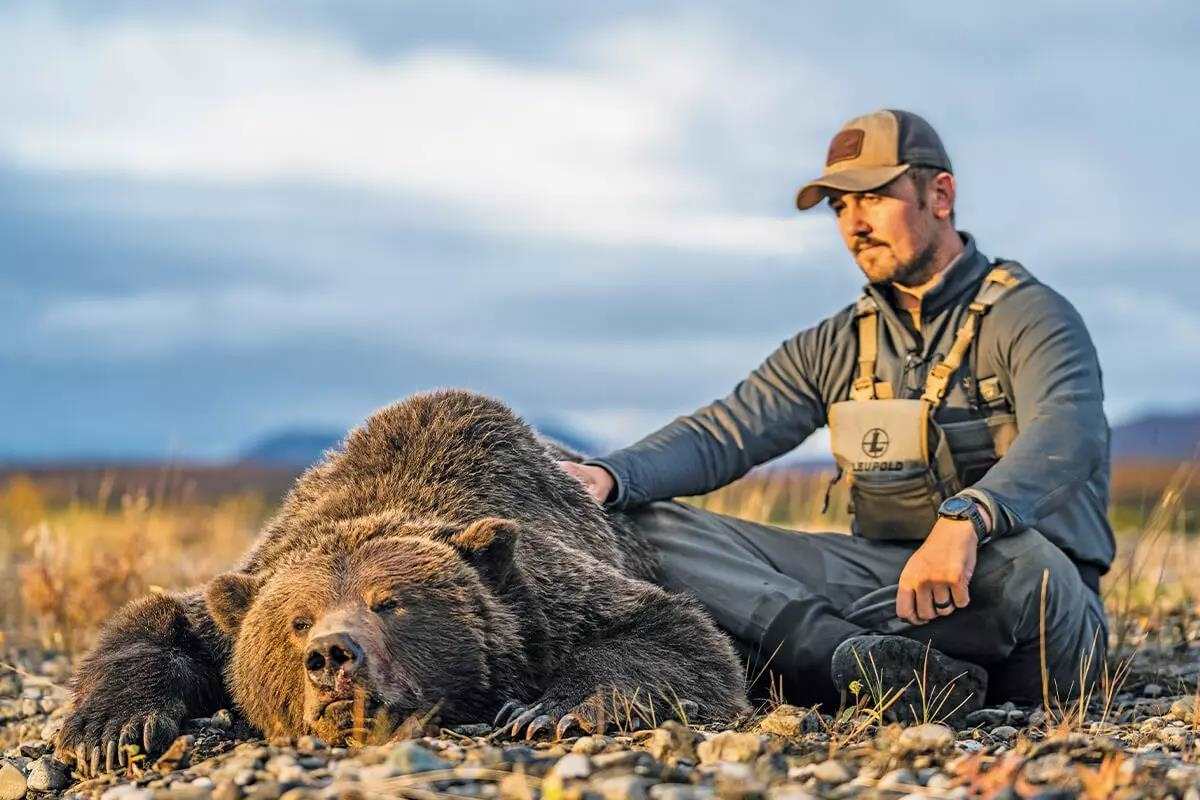hunter admires his grizzly kill