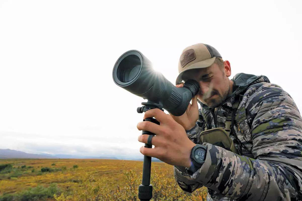 man peering through spotting scope