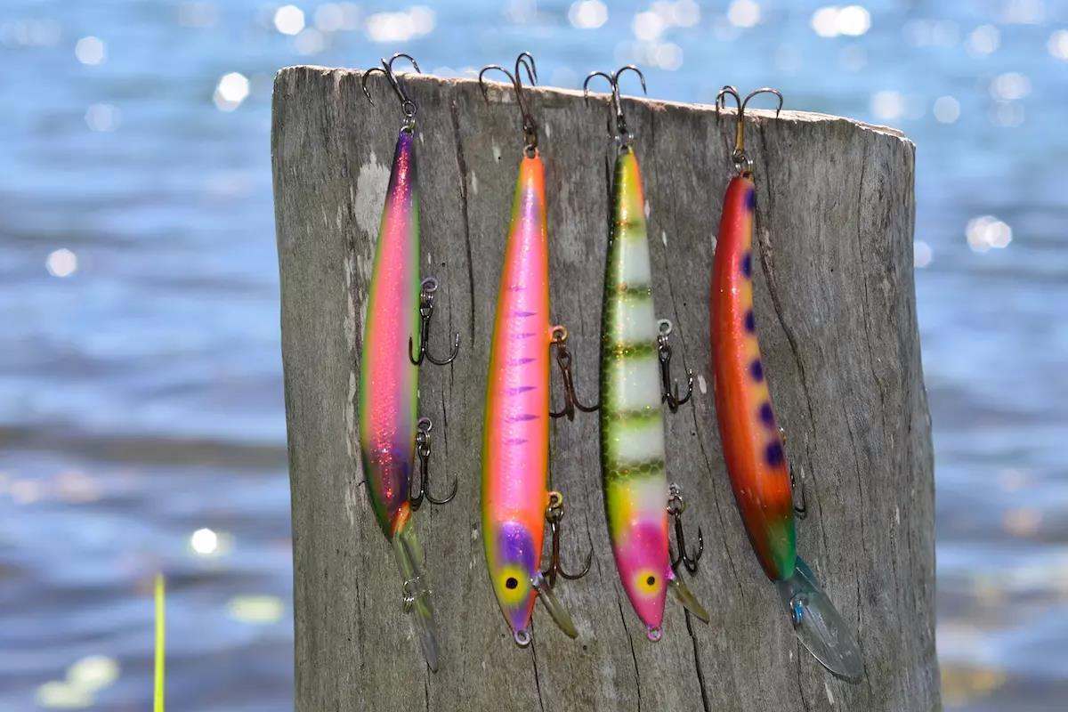 Four custom crankbaits hang from a post on a dock. 