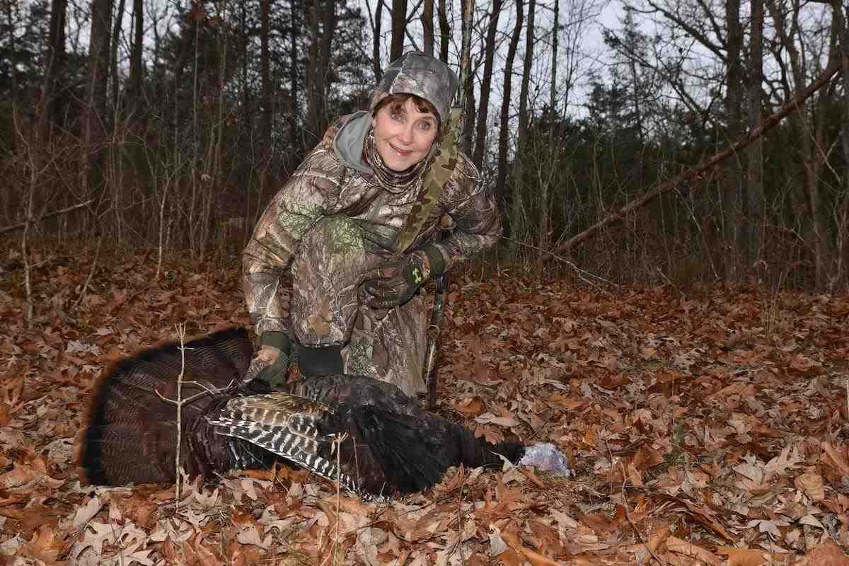 A hunter poses with a downed wild turkey. 