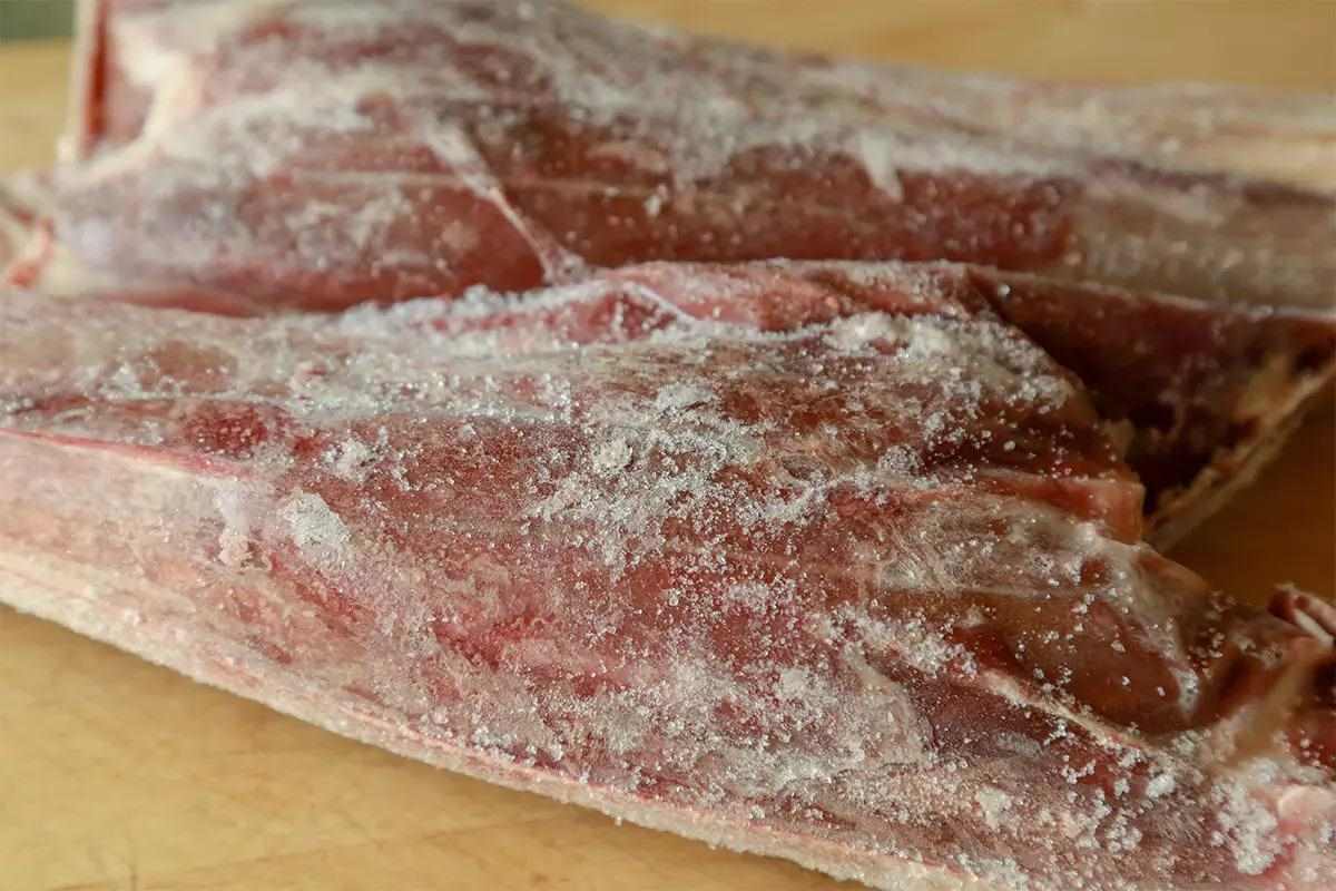 Freezer burned meat on a wooden table.