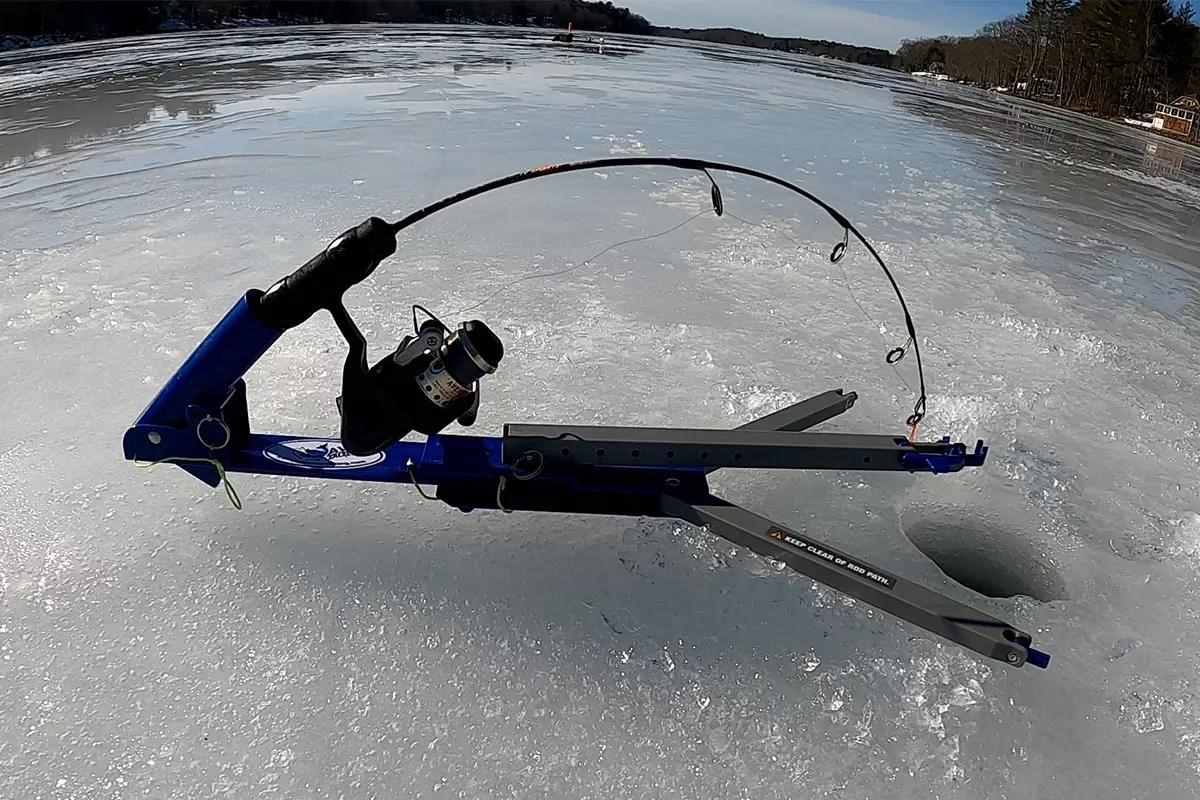 A ice fishing poles set up in a jig trap on the ice to catch fish. 