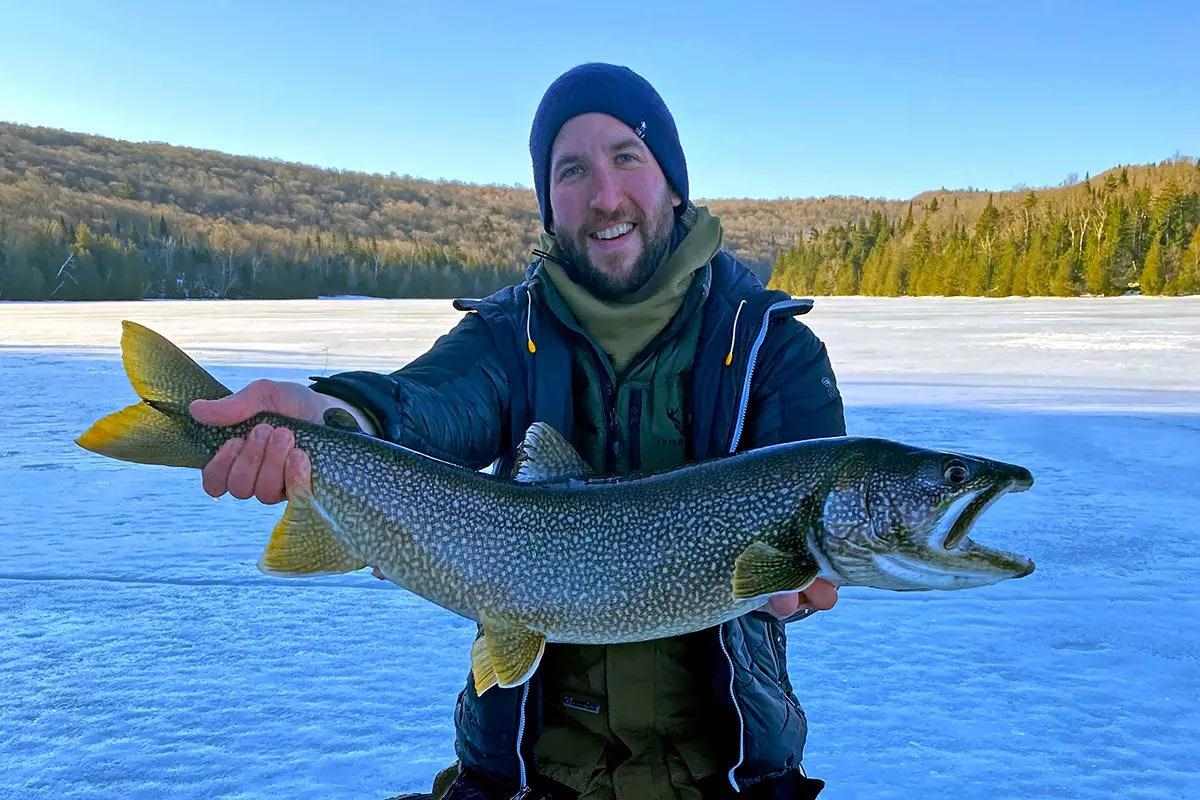An ice angler holding a large lake trout for the camera. 