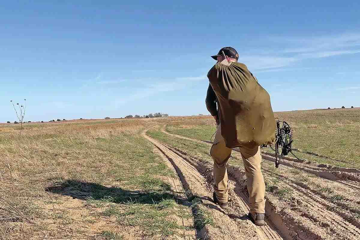bowhunter walking into Kansas hunting spot carrying 3-D buck decoy