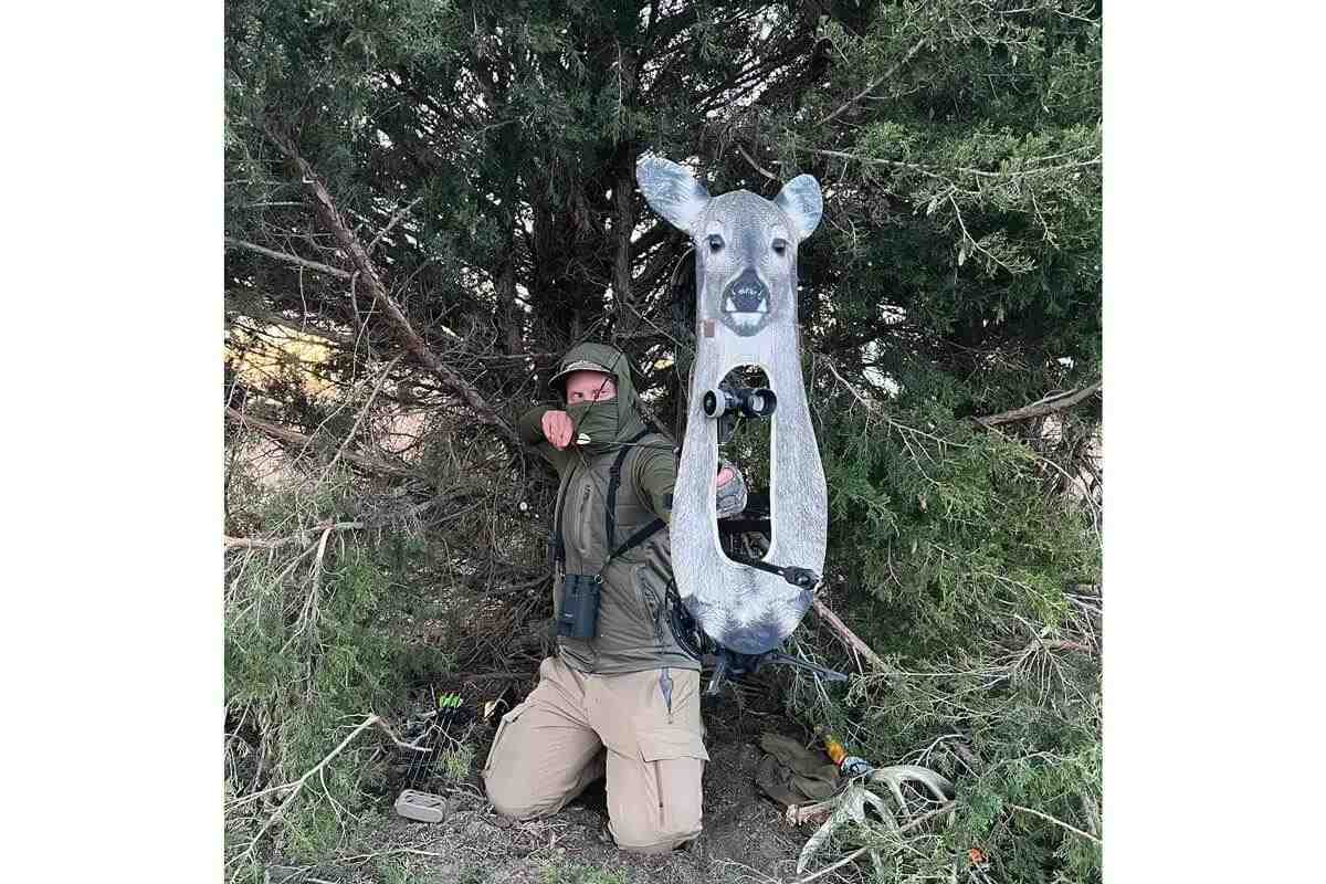 bowhunter at full draw using bow-mounted deer decoy