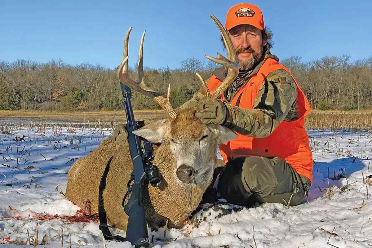 hunter with big buck on snow
