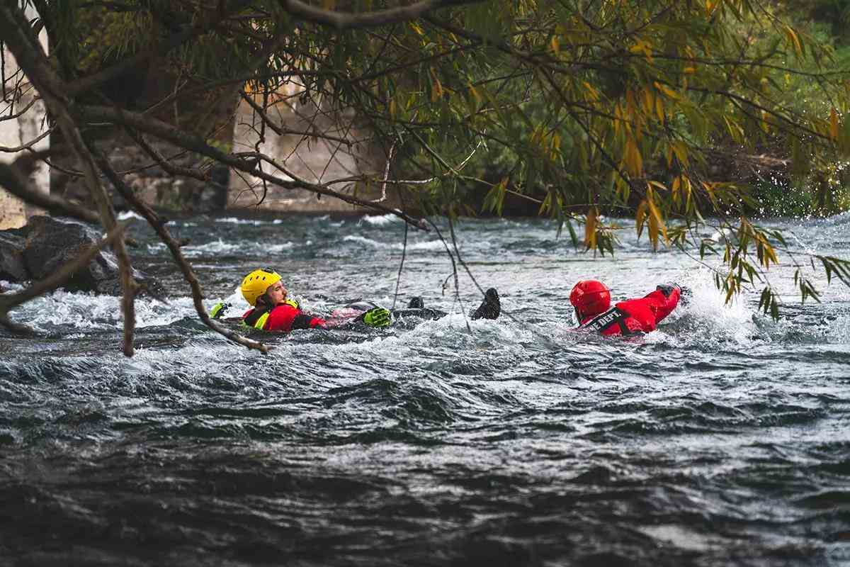 A river rescue professional swimming toward a man swimming in a dangerous whitewater situation.