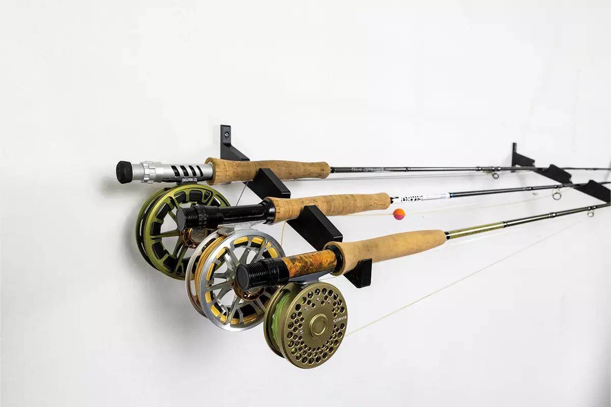 A fly-rod rack with three rods and reels hung on a wall. 