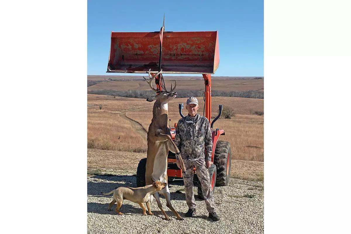 bowhunter with downed buck and his dog