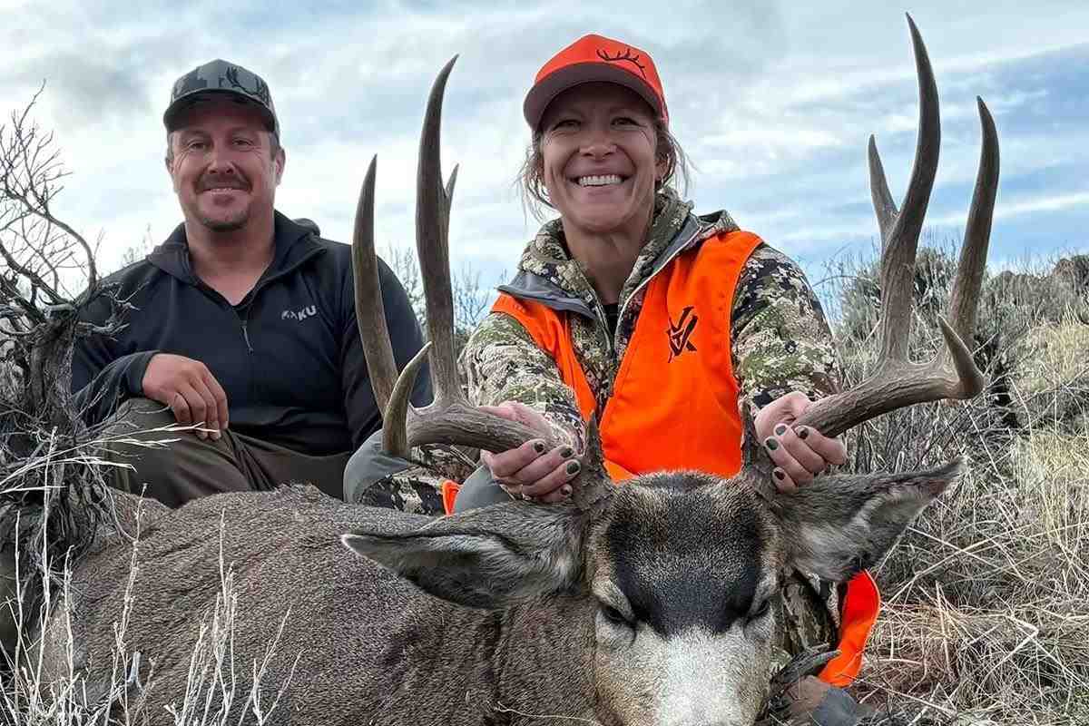 A hunter and her husband pose with a harvested mule deer. 