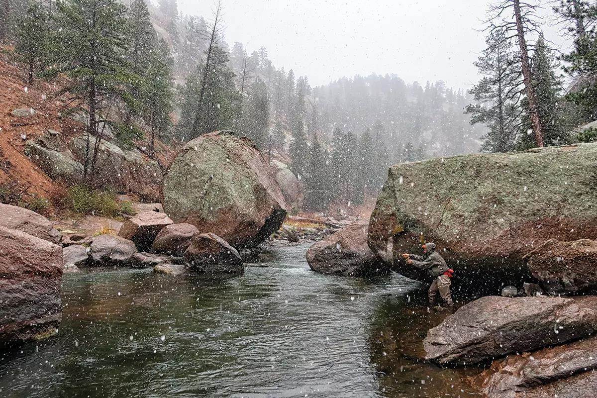 A fly angler nymphing a boulder-strewn spot on a river canyon. 
