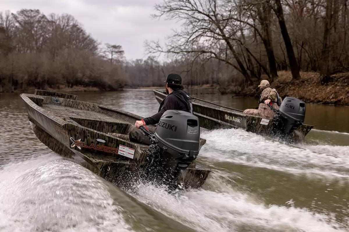 Two boaters race along each other on a small river.