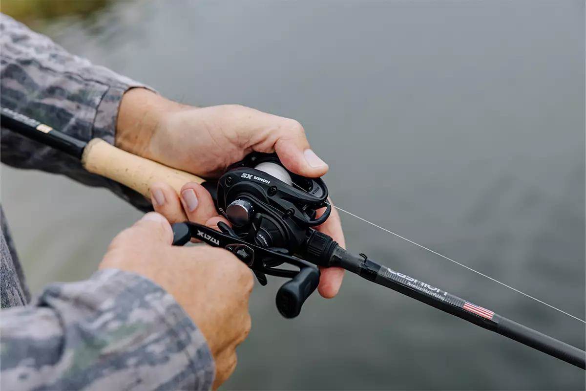 An angler holds a baitcasting rod and reel. 