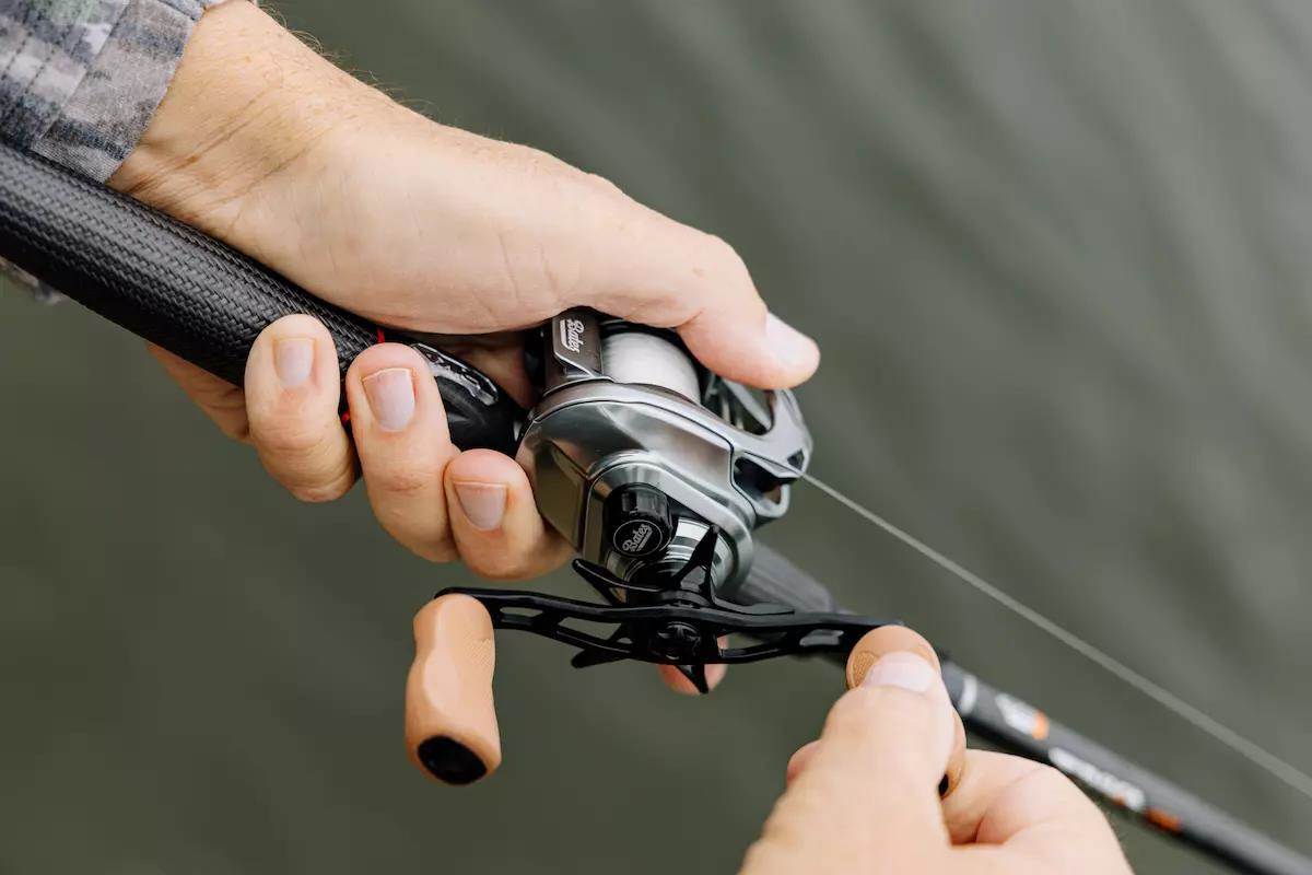 An angler holds a baitcasting rod and reel. 
