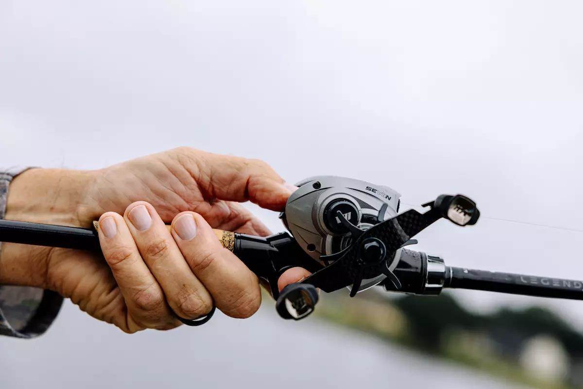 An angler holds a baitcasting rod and reel. 