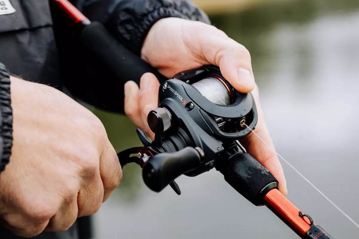 An angler holds a baitcasting rod and reel. 
