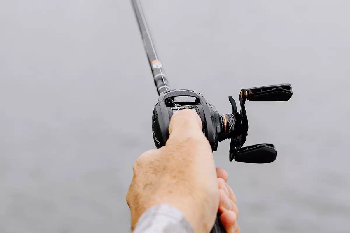 An angler holds a baitcasting rod and reel. 