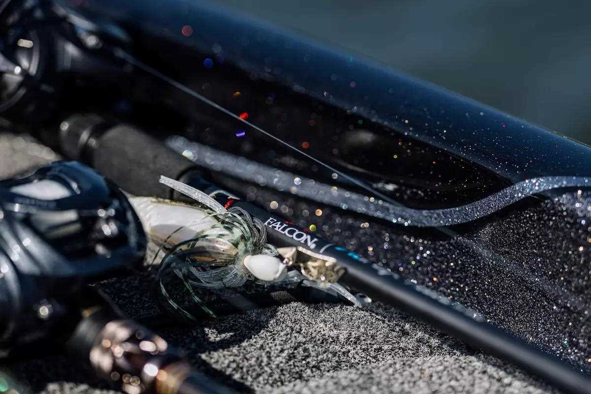 A baitcasting rod and reel lie on a bass boat deck.